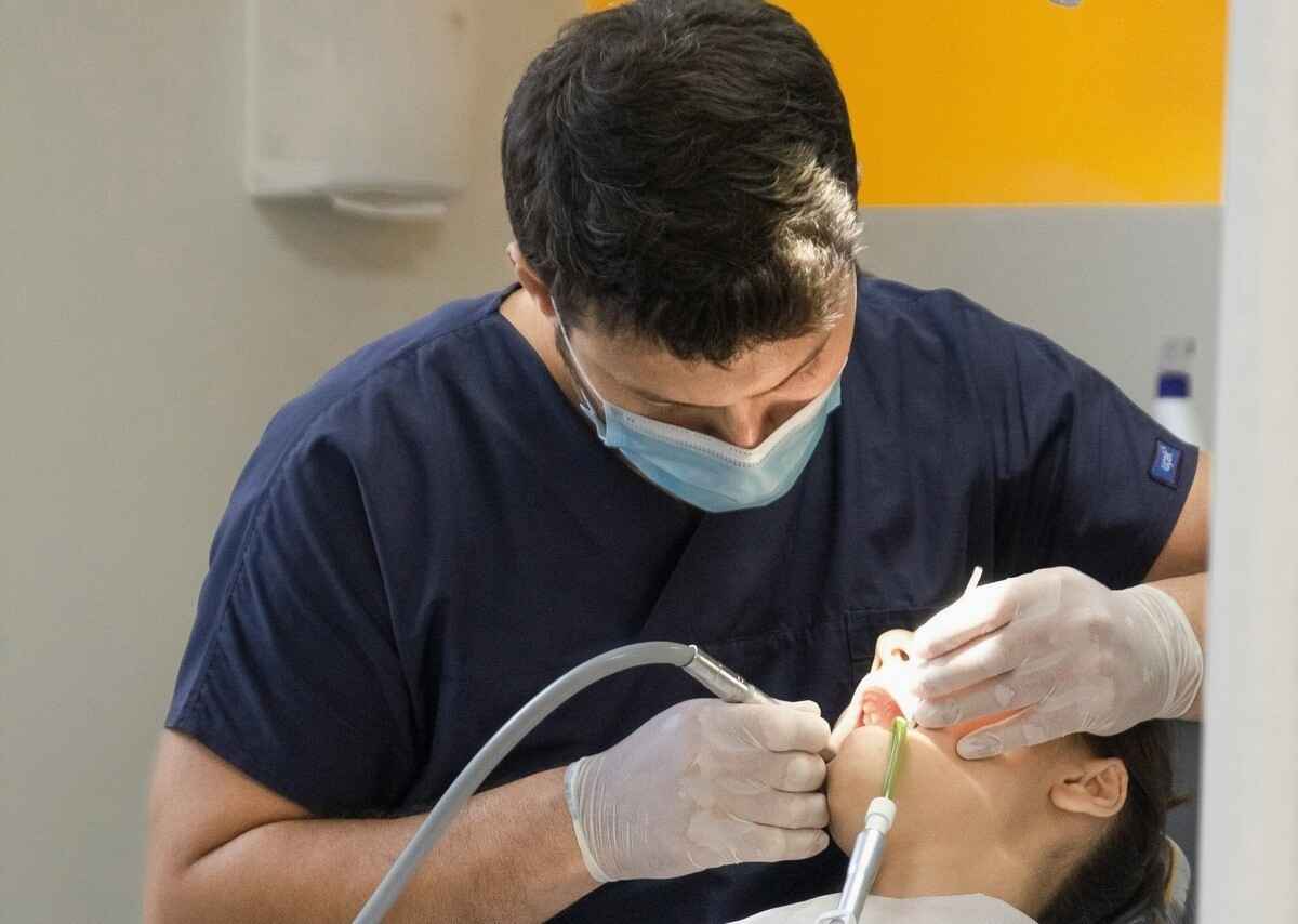 A calm dental patient smiling in the chair while a gentle dentist offers reassurance in a cozy, welcoming office.