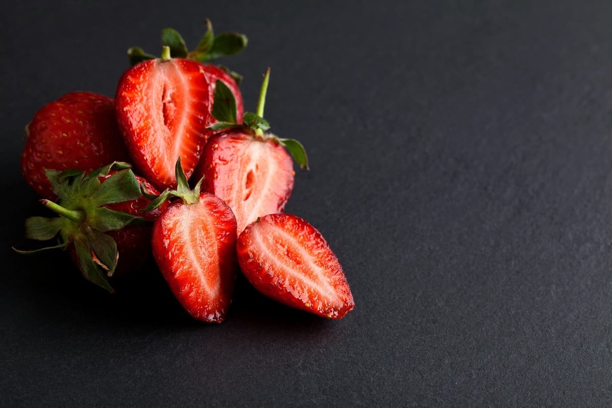 Fresh strawberries on a black background – can you eat strawberries after dental implant surgery?